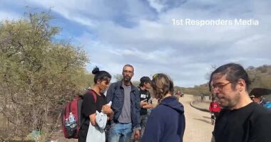 The migrant man (second from left) told the reporter 'you are going to know who I am'