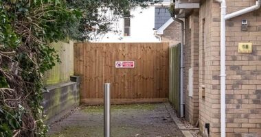 The eight-foot tall fence (pictured, with a red and white sign) was built across a path into the estate to deter anti-social behavior after residents complained