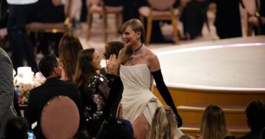 Taylor Swift is pictured walking to her seat, as Trevor Noah joked that she was impacting the economy of each table she passed