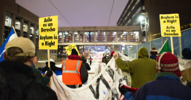immigration protester carry signs that say "asylum is a right"