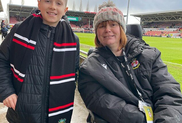 Wrexham fan Theo Smith, 10, poses with Kerry Evans, right, who established a 120-seat section at the Racecourse Ground for fans with autism and physical challenges to watch football