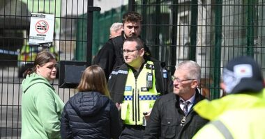 Police speak to worried parents outside Ysgol Dyffryn Aman in Wales after classrooms were put in 'lockdown' following the incident