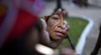 A Maka Indigenous woman puts on make-up before protesting for the recovery of ancestral lands in Asuncion, Paraguay, Wednesday, Feb. 28, 2024. Leader Mateo Martinez has denounced that the Paraguayan state has built a bridge on their land in El Chaco's Bartolome de las Casas, Presidente Hayes department. (AP Photo/Jorge Saenz)