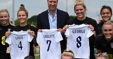 Prince William poses with England players including Rachel Daly (2nd L) and Millie Bright (2nd R) after receiving a gift of three England shirts, each bearing the name of one of his children, whilst visiting the England Women's football team at St. George's Park on June 15, 2022 in Burton upon Trent