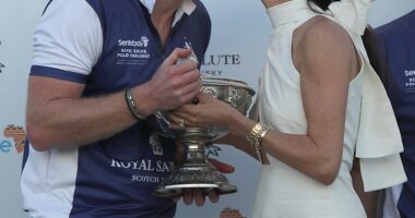 The Duchess of Sussex presents the trophy to her husband, the Duke of Sussex after his team the Royal Salute Sentebale Team