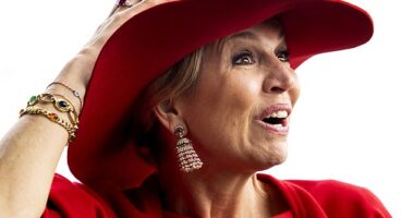 Queen Máxima of the Netherlands held onto her crimson hat today as she attended a restaurant opening in windy Amsterdam