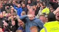 A Burnley supporter (centre, hooded top) has been charged by police for tragedy chanting after being seen making what is alleged to be aeroplane gestures at Man United fans on Saturday