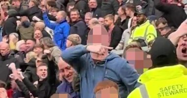 A Burnley supporter (centre, hooded top) has been charged by police for tragedy chanting after being seen making what is alleged to be aeroplane gestures at Man United fans on Saturday