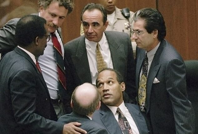 OJ Simpson is surrounded by his defense attorneys, from left, Johnnie L. Cochran Jr., Peter Neufeld, Robert Shapiro, Robert Kardashian, and Robert Blasier, seated at left, at the close of defense arguments in his murder trial, Thursday, September 28, 1995, in Los Angeles
