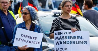 People hold banners that read "Direct democracy" and "No to mass immigration, yes to remigration" as far-right protesters march through the streets of Solingen