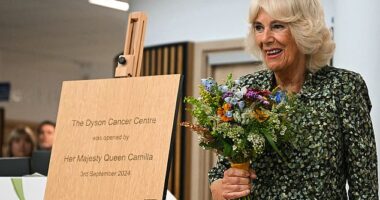 Queen Camilla, pictured holding a bunch of flowers, looked delighted to return to work today