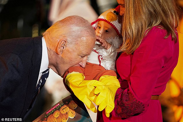 Joe Biden playfully bites a baby during trick-or-treating at the White House