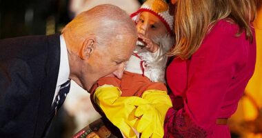 Joe Biden playfully bites a baby during trick-or-treating at the White House