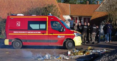 French gendarmes today stand by a firefighter's vehicle as rescuers tend to migrants who survived a deadly boat sinking in their attempt to reach Britain