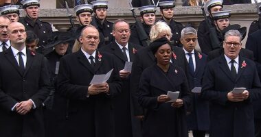 Stephen Flynn, left, stood silently as his fellow political leaders sung hymns and the national anthem at the Cenotaph