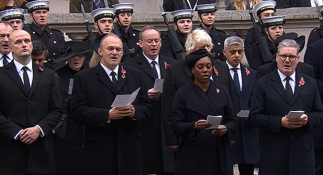 Stephen Flynn, left, stood silently as his fellow political leaders sung hymns and the national anthem at the Cenotaph