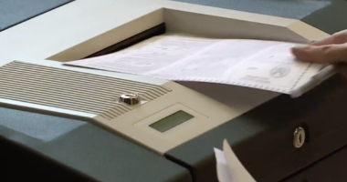 voting inserting ballot into scanner