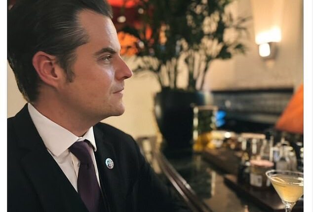 The former congressman is shown in a dark suit sitting at a bar with a martini in front of him.