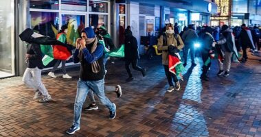 Demonstrators run with Palestinian flags ahead of the UEFA Europa League match between Ajax and Maccabi Tel Aviv