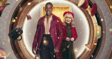 Ncuti Gatwa as the Doctor and Nicola Coughlan as Joy wearing red and green outfits with floating objects and glitter