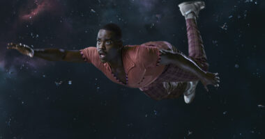 Ncuti Gatwa as the Fifteenth Doctor in tartan trousers and an orange top and floating in space