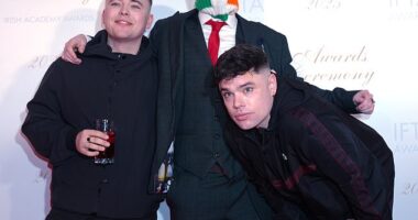 Contoroversial Irish group Kneecap have incited their fans to turn up at court to support them when a band member faces a terror charge. Pictured: Liam O'Hanna, left, with bandmates DJ Provai (centre) and Moglai Bap (right)
