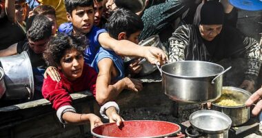 Displaced Palestinians receive hot meals distributed by aid organizations in Jabalia refugee camp of Jabalia, Gaza on May 5, 2025