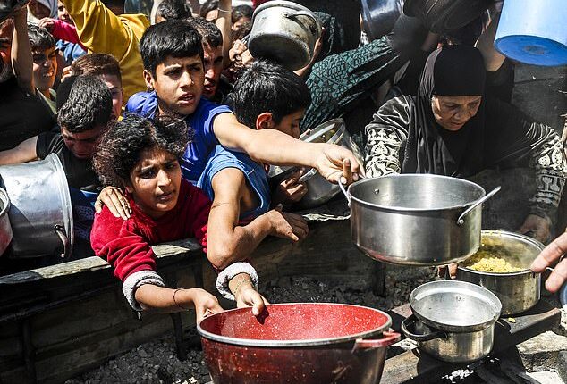 Displaced Palestinians receive hot meals distributed by aid organizations in Jabalia refugee camp of Jabalia, Gaza on May 5, 2025