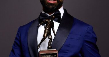 Salah was seen in a navy jacket with black lapels, a white shirt and a bow tie as he posed with the trophy