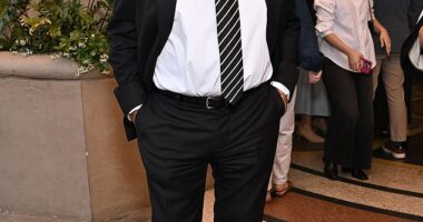 The legendary singer stepped out in a classic black suit with a white dress shirt, a black and white striped tie, black belt, black pants and black shoes