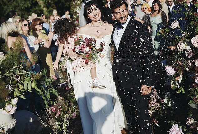 Blushing bride Daisy Lowe cradled her daughter Ivy as she walked down the aisle with new husband Jordan Saul in striking new wedding snaps