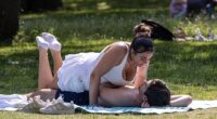 A man and woman enjoy the hot weather at Green Park in London this morning