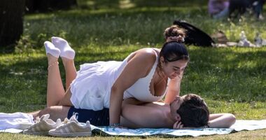 A man and woman enjoy the hot weather at Green Park in London this morning