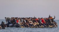 A migrant holds a mobile phone aloft for a selfie from the bow of a dinghy bound for Britain early this morning