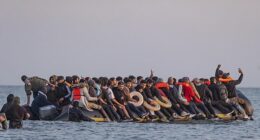 A migrant holds a mobile phone aloft for a selfie from the bow of a dinghy bound for Britain early this morning