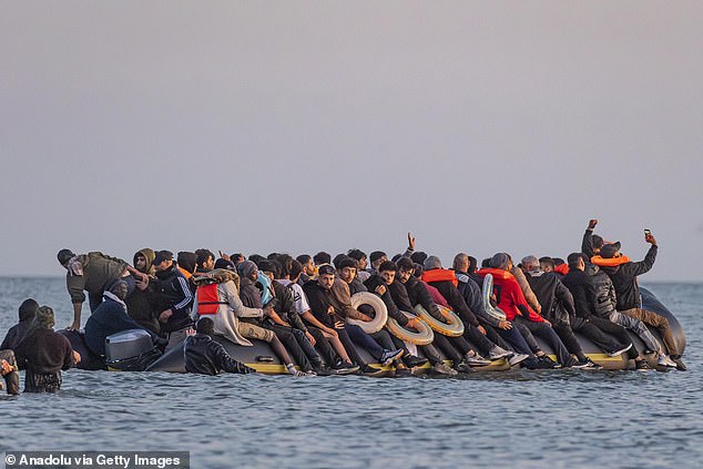 A migrant holds a mobile phone aloft for a selfie from the bow of a dinghy bound for Britain early this morning