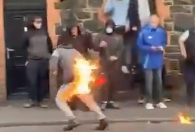This is the shocking moment one protestor went up in flames as rioters hurled petrol bombs, fireworks and masonry at police officers