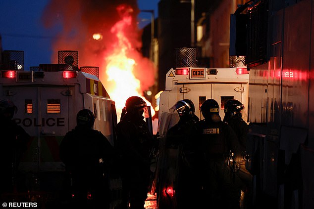 Riot police clash with masked yobs in Ballymena, Northern Ireland, tonight during a riot over an alleged sexual assault