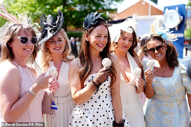 They're prepared! A group of glamorous ladies show off their handheld electric fans as they arrive at Ascot