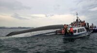 Relief personnel gathered around a capsized tourist boat, which had been carrying 53 passengers when it capsized - of these at least 34 are believed to have died