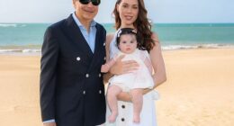 Wall Street billionaire John Paulson is all smiles in sun-soaked family portrait posted to Instagram on Friday as he is seen wrapping his arm around his glamorous, much-younger fiancée who is holding their baby daughter