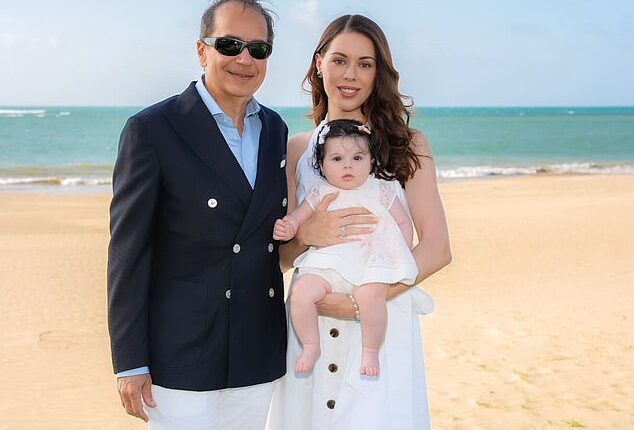 Wall Street billionaire John Paulson is all smiles in sun-soaked family portrait posted to Instagram on Friday as he is seen wrapping his arm around his glamorous, much-younger fiancée who is holding their baby daughter