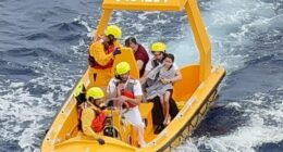 A five-year-old girl sits on the ship's doctor's knee after she and her father were rescued when they fell into the ocean from the Disney Dream cruise ship on Sunday morning