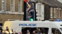A protestors jumps up and down on the roof of a police van at a protest on July 17 outside The Bell Hotel