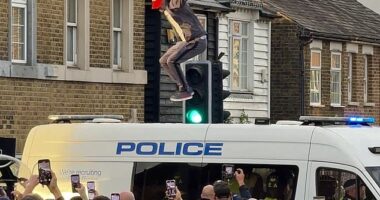 A protestors jumps up and down on the roof of a police van at a protest on July 17 outside The Bell Hotel