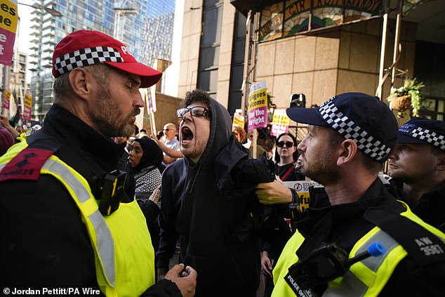 A protester who was asked to remove his face mask shouts at a police officer whilst taking part in the Stand Up to Racism rally outside the Britannia International Hotel in Canary Wharf