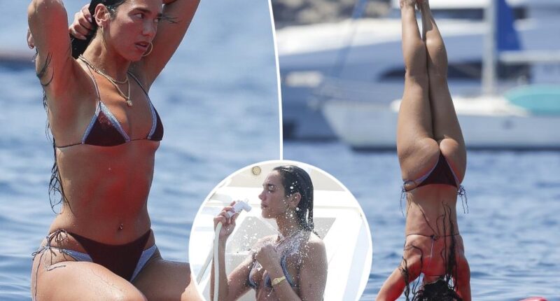 Dua Lipa flaunts her abs during paddleboard yoga in Ibiza