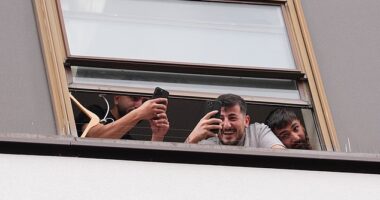 People believed to be migrants have been seen filming and laughing from a window at the Thistle City Barbican Hotel in London