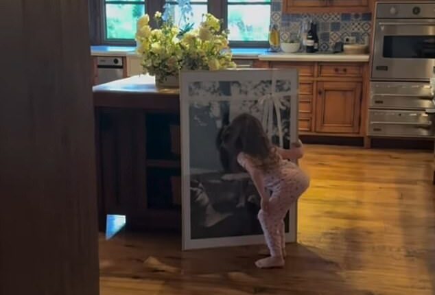 Lilibet, four, can be seen examining a new portrait of the family's beloved dog Guy, who passed away earlier this year, at the Sussexes' Montecito mansion in a clip shared on Meghan's Instagram story today