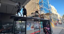 Three men splattered in paint were spotted dancing on top of a bus stop outside Ladbroke Grove station, near Portobello Road market